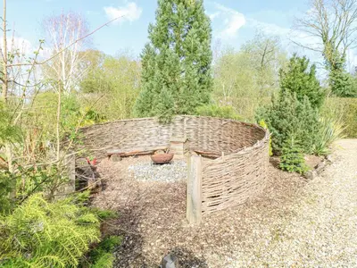 a wicker bench in the middle of a garden at Damsel Shepherds Hut in Badwell Ash
