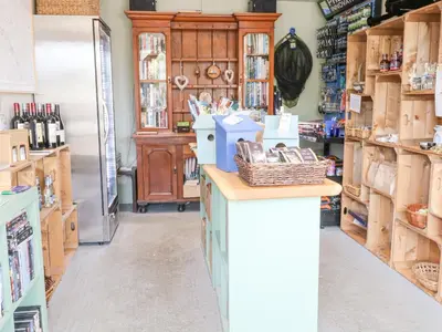 a store with a refrigerator and a counter in a room at Damsel Shepherds Hut in Badwell Ash