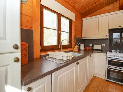 a kitchen with white cabinets and a sink at Wagtail Lodge in Langham
