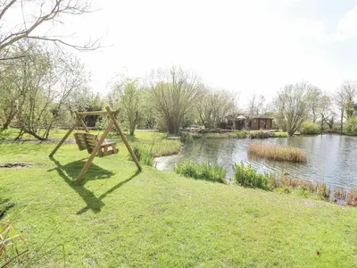 a bench sitting in the grass next to a river at Wagtail Lodge in Langham
