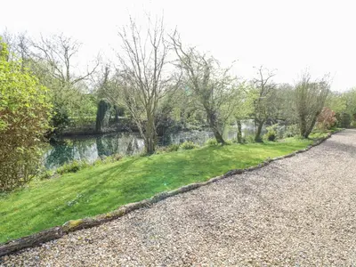 a gravel road next to a river with trees at Wagtail Lodge in Langham