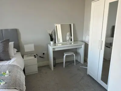 a bedroom with a desk with a mirror and a bed at Bright, spacious 1 bedroom flat in Brentwood