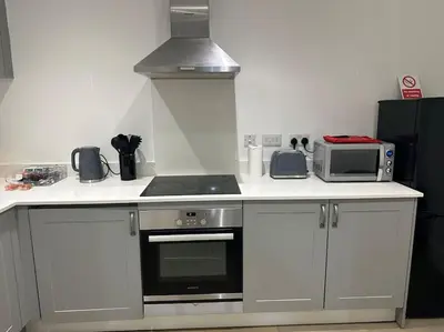a kitchen with a stove and a microwave at Bright, spacious and modern flat in Brentwood
