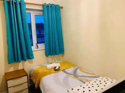 a bedroom with blue curtains and a bed with a stuffed animal on it at Contractors and families welcome in Earith