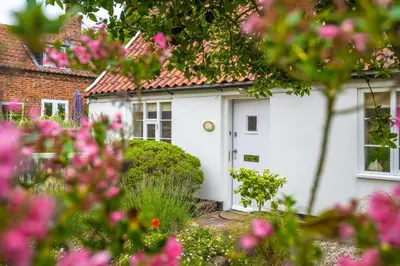 a white house with a white door and pink flowers at Myrtle Cottage 4 in Friston
