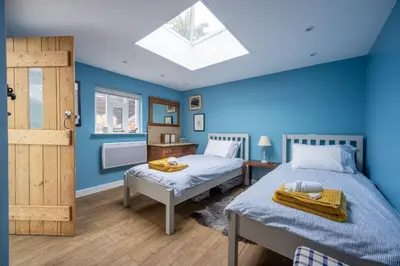 a bedroom with two beds with blue walls and a skylight at Myrtle Cottage 4 in Friston