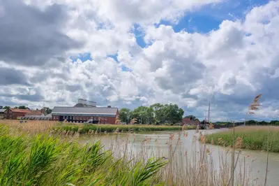 a building on the side of a river with a field at Myrtle Cottage 4 in Friston