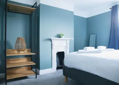 a blue bedroom with a bed and a fireplace at Stylish 3x bed house in Soham in Soham