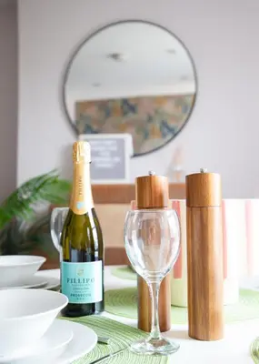 a table with a bottle of wine and a glass at Stylish 3x bed house in Soham in Soham