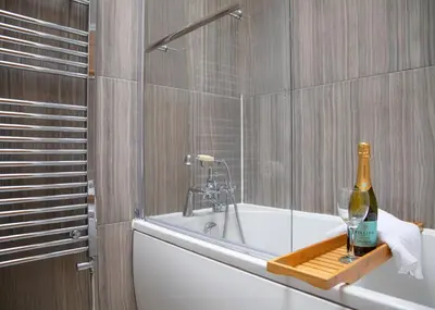a bathroom with a bottle of wine on a bath tub at Stylish 3x bed house in Soham in Soham