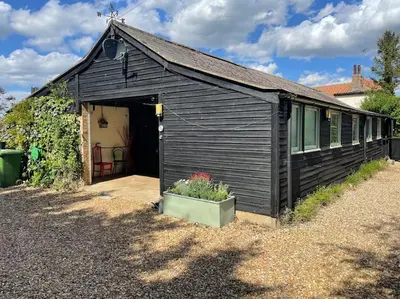 a black shed with a door and a plant in a pot at Ivy Cottage in Salters lode