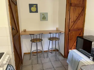 a kitchen with two bar stools and a television at Ivy Cottage in Salters lode