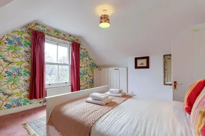 a bedroom with a bed with red curtains and a window at Pass the Keys Spacious Victorian Home with Free Parking in Cambridge
