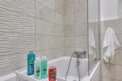 a bathroom with a bath tub with bottles of soap at Chelmsford City Central Ground Floor Apartment Next To Town Centre in Chelmsford