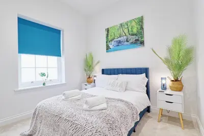 a white bedroom with a bed with two towels on it at Chelmsford City Central Ground Floor Apartment Next To Town Centre in Chelmsford