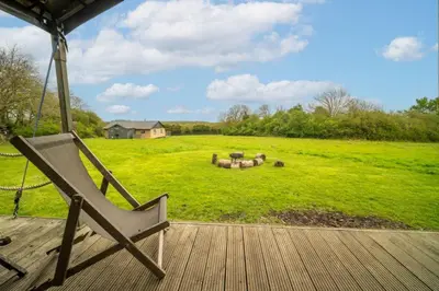 a chair sitting on a porch with a large field at Cuckoo - Sweffling Hall in Rendham