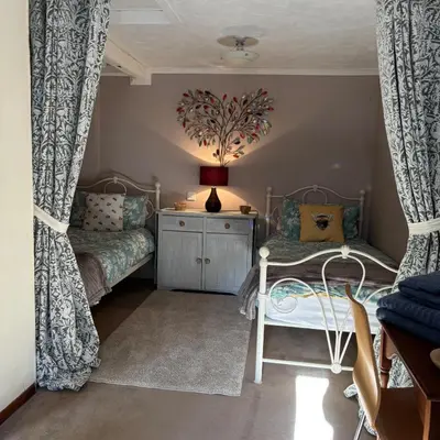 a bedroom with two beds and a dresser with curtains at 2 Bed Barn - Sleeps 4 - Pets - Parking - Wifi in Downham Market