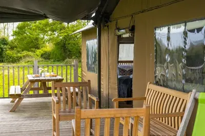 a porch with two benches and a table on a deck at Kestrel - Sweffling Hall in Rendham
