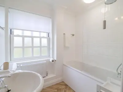 a white bathroom with a tub and a sink at 23 Church Farm Lane in Halesworth