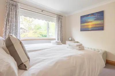 a bedroom with a large white bed with a window at 5 Toller Close, Orford in Orford