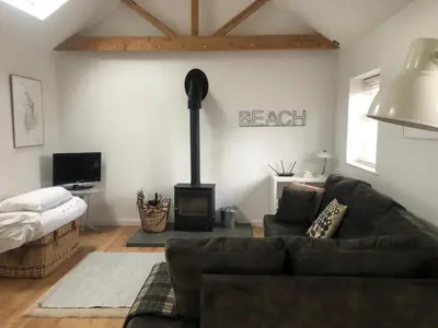 a living room with a couch and a wood stove at The studio spring house in Alderton