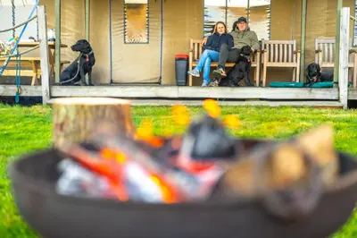 a man and woman sitting on a bench with two dogs at Linnet - Sweffling Hall in Rendham
