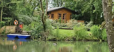 a wooden cabin on the side of a river at Captivating 1-Bed Cabin in Newmarket in Newmarket
