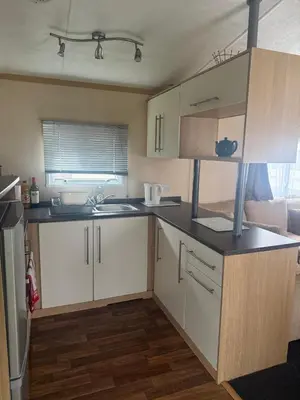 a small kitchen with white cabinets and a sink at 6 Bed Static Carvan Seawick Holiday Park in Saint Osyth
