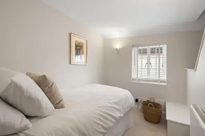 a white bedroom with a bed and a window at Beautiful period property in historic town in Braintree