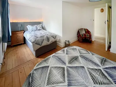 a bedroom with a bed and a wooden floor at Sandy Toes Cottage in Beechamwell