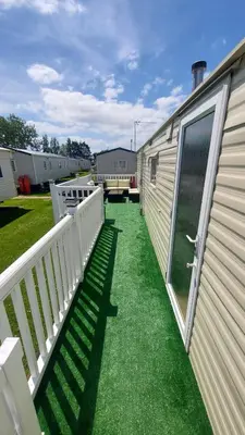a backyard with a fence and grass next to a trailer at SKYLA VISTA Deluxe in Clacton-on-Sea