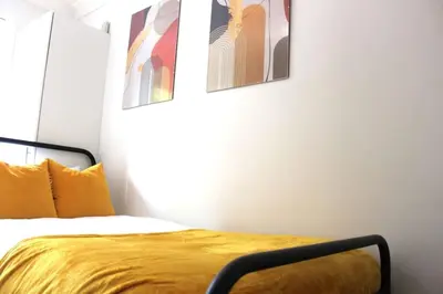 a bedroom with a bed with two pictures on the wall at STN - Bishops's Stortford - Free Gated Parking - Two Bed Apartment - Perfect location for Stansted Airport in Bishops Stortford