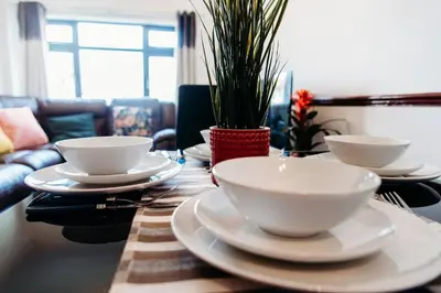a wooden table with white bowls and plates on it at Sunny Beachside Apt with Free Parking in Southend-on-Sea