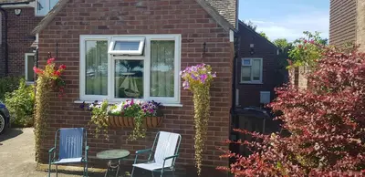 a house with two chairs and a window with flowers at Mermaid Cottages in Frinton-on-Sea