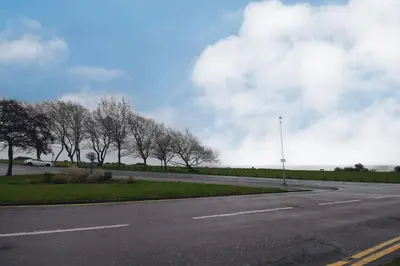 an empty road with trees on the side of the road at Mermaid Cottages in Frinton-on-Sea