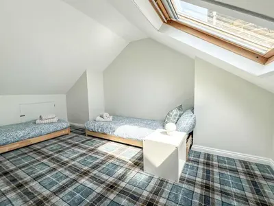 a attic bedroom with two beds and a window at Stunning Cottage in the Heart of Old Leigh - Pass the Keys in Southend-on-Sea