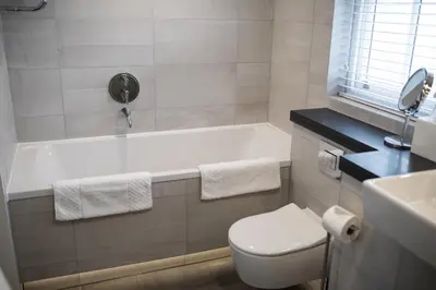 a bathroom with a tub and a toilet and a sink at Bedford Lodge Hotel & Spa in Newmarket