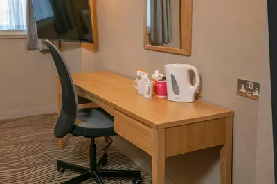 a wooden desk with a chair and a television at Best Western Heath Court Hotel in Newmarket