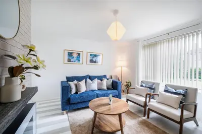 a living room with a blue couch and chairs at Kingside Residence Stevenage in Stevenage