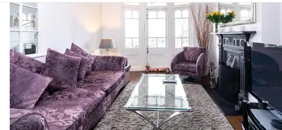a living room with purple couches and a tv at Stunning sea views from rooms and terraces in Leigh-on-Sea