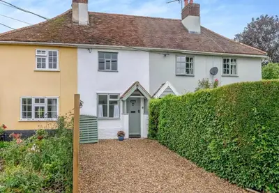 a white house with a hedge in front of it at Meadowland Holiday Cottage in Eye