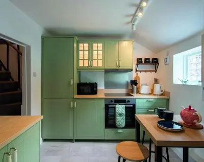a kitchen with green cabinets and a wooden table at Meadowland Holiday Cottage in Eye