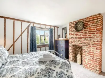a bedroom with a bed and a brick fireplace at Meadowland Holiday Cottage in Eye