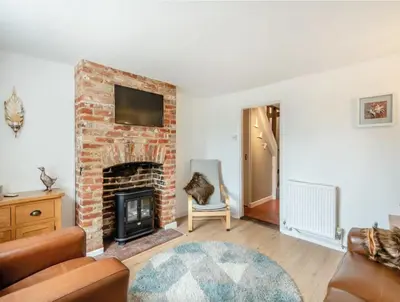 a living room with a brick fireplace with a tv at Meadowland Holiday Cottage in Eye