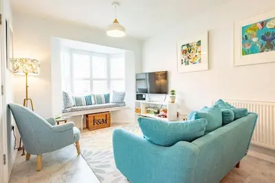a living room with a blue couch and two chairs at The Salty Dog, Aldeburgh in Aldeburgh
