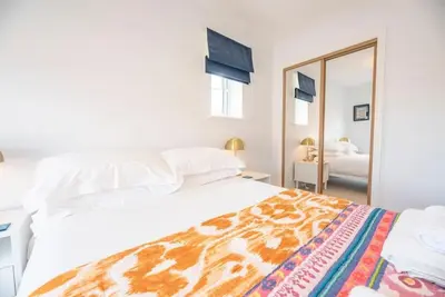 a bedroom with a large white bed and a mirror at The Salty Dog, Aldeburgh in Aldeburgh