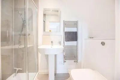 a white bathroom with a sink and a shower at The Salty Dog, Aldeburgh in Aldeburgh