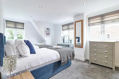 a bedroom with a bed and a dresser and windows at LMV Property - Modern Luxury Family Home in Theydon Bois With London Skyline Views in Theydon Bois