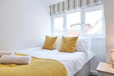 a white bed with yellow pillows and a window at LMV Property - Modern Luxury Family Home in Theydon Bois With London Skyline Views in Theydon Bois