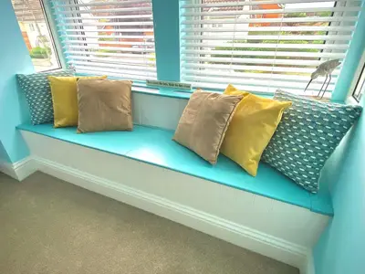 a blue bench with pillows sitting in a window at 2 Bedroom Apartment with Garden, Close to Beach in Southend-on-Sea